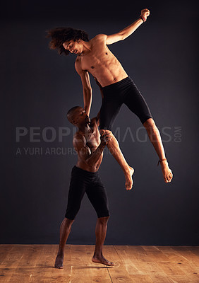 Buy stock photo Two male contemporary dancers performing a dramatic pose in front of a dark background