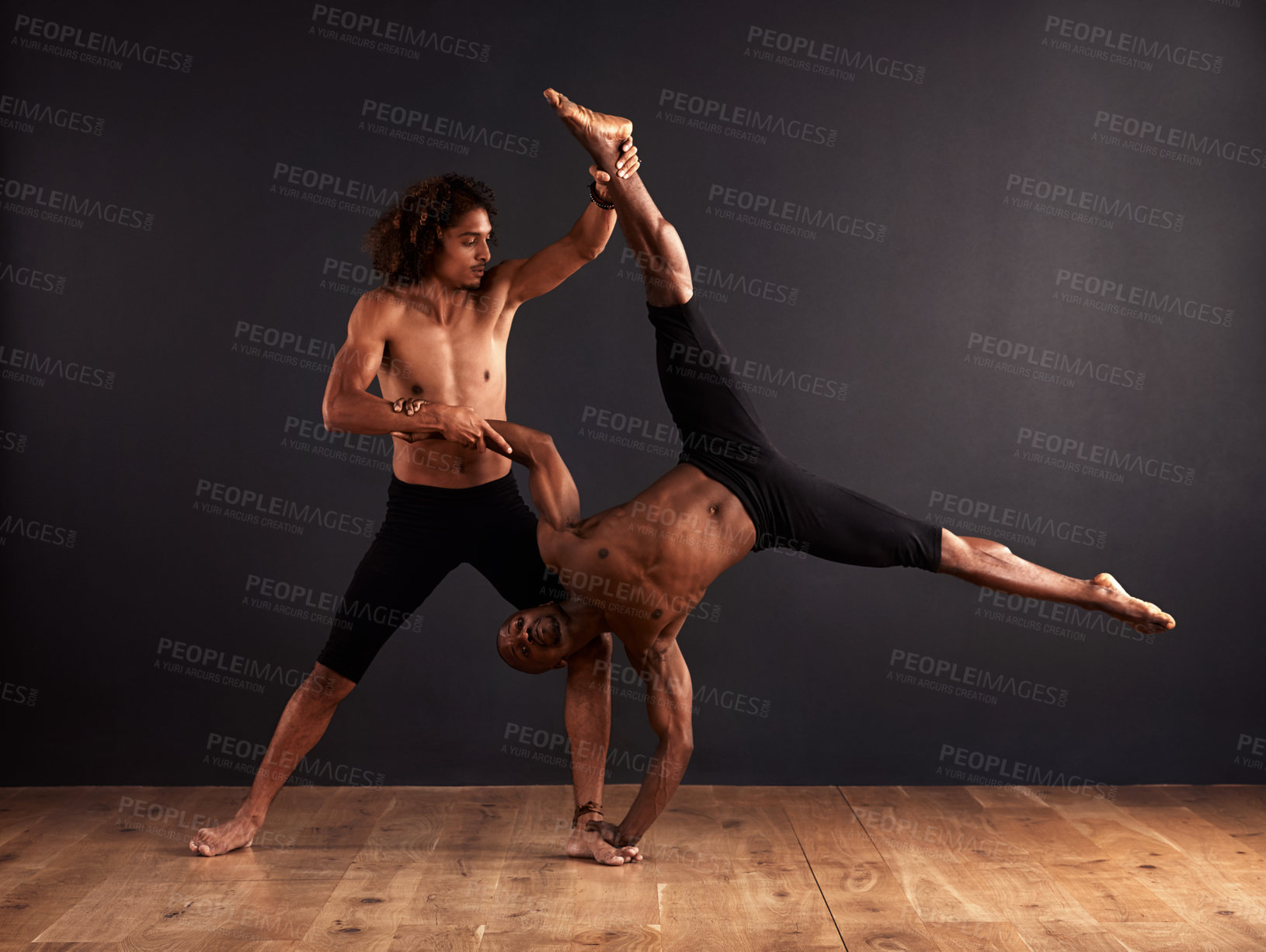 Buy stock photo Two male contemporary dancers performing a dramatic pose in front of a dark background