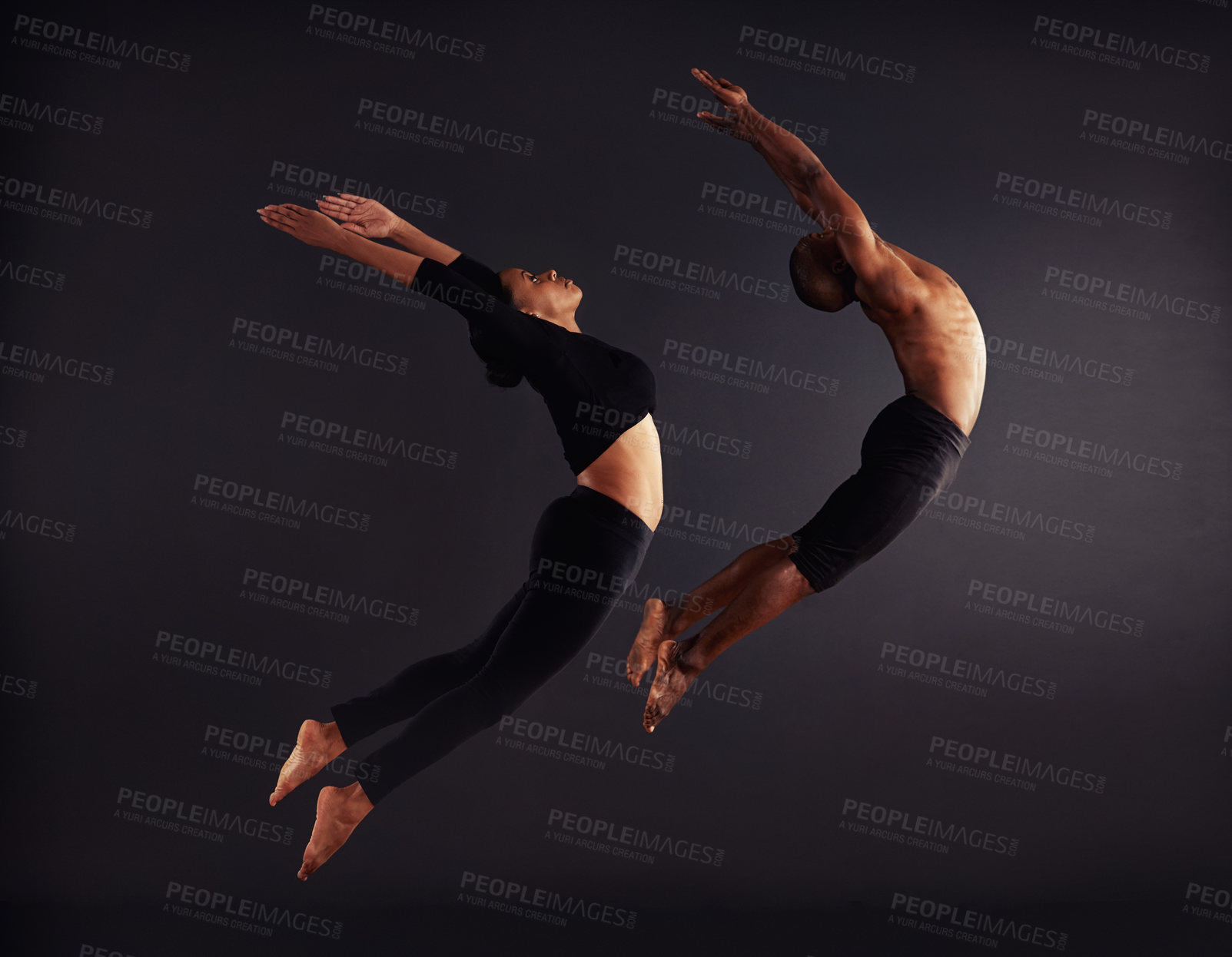 Buy stock photo A female and male contemporary dancer performing a dramatic pose in front of a dark background