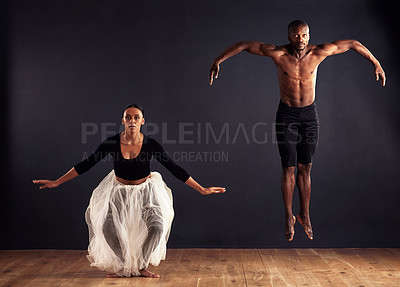 Buy stock photo A female and male contemporary dancer performing a dramatic pose in front of a dark background