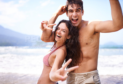 Buy stock photo Fun, peace sign and portrait of couple at beach for tropical holiday adventure, relax or bonding together. Love, happy man and woman on romantic date with ocean, blue sky and smile on nature vacation