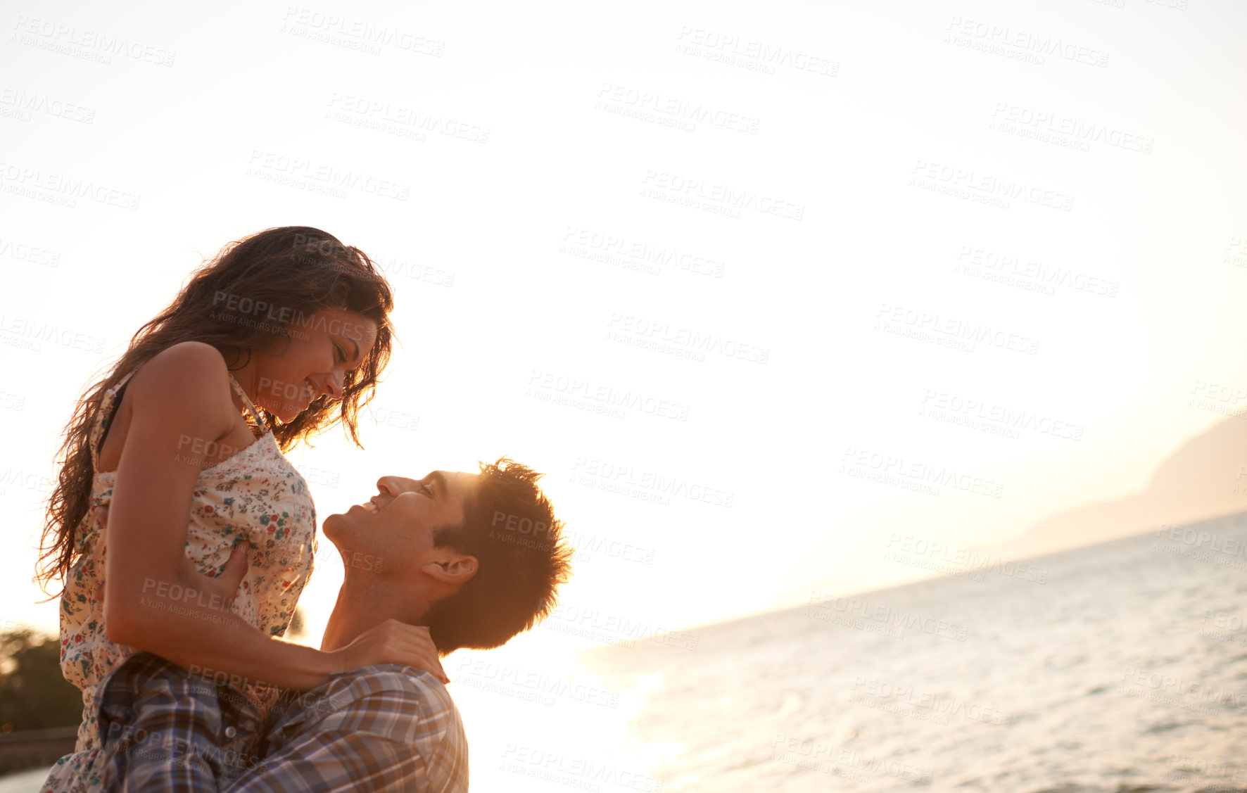 Buy stock photo Beach, man lifting woman and ocean for travel, anniversary or date with bonding, love and support. Happy, freedom and fresh air in nature, couple outdoor and sunset, trust and hug in relationship