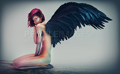 Buy stock photo Shot of a gorgeous woman with feathered wings in a fantasy-like setting