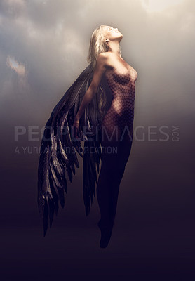 Buy stock photo Shot of a gorgeous woman with feathered wings in a fantasy-like setting