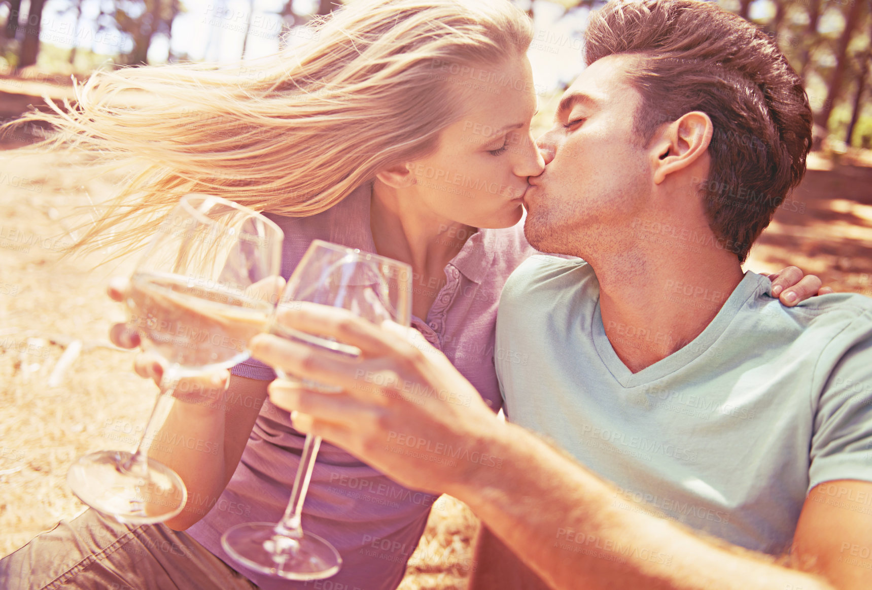 Buy stock photo Happy couple, champagne and kiss outdoors for celebration of engagement,  romantic, cheers and in nature. Glassware, summer and toast to love with man, woman and spring date in forest together. 