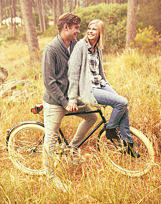 Buy stock photo Love, smile and couple on bicycle in countryside together for romantic date outdoor or anniversary. Nature, grass or field with happy young man and woman riding bike in autumn park for travel