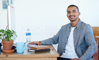 Buy stock photo Portrait of a handsome young man working at his computer in an office. The commercial designs displayed represent a simulation of a real product and have been changed or altered enough by our team of retouching and design specialists so that they don't have any copyright infringements