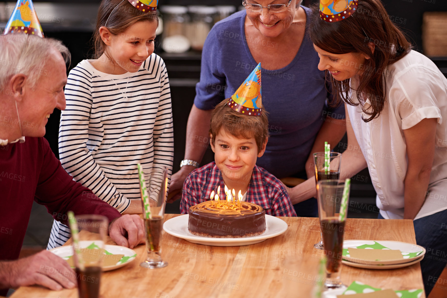 Buy stock photo Family, birthday cake and smile of boy, parents and grandparents together with youth and candles. Happy, kid and dessert with children and celebration with event food and party hats at a table