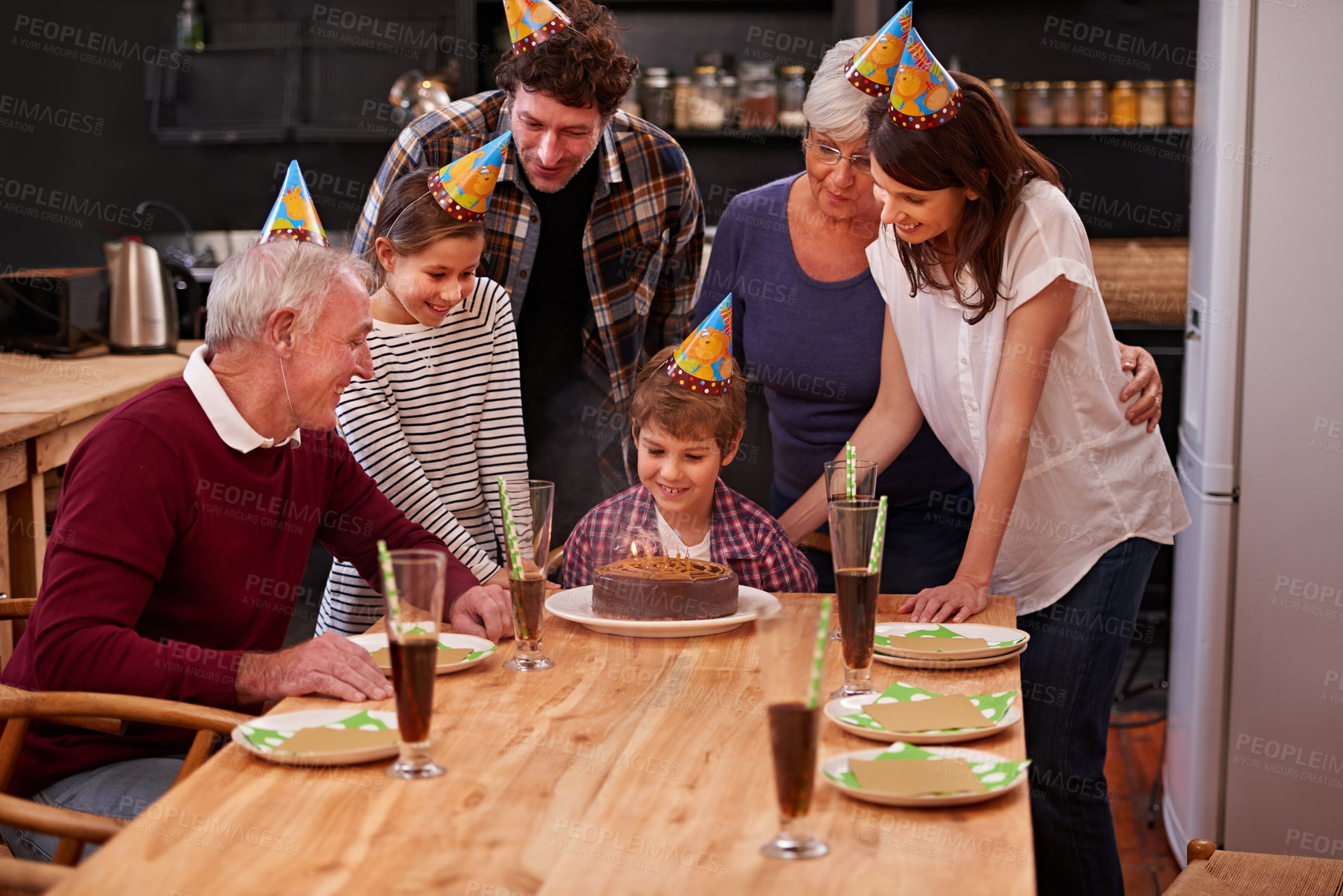 Buy stock photo Family, birthday cake and happy kid with mom, dad and grandparents together with people and candles. Youth, smile and dessert with children and celebration with event food and party hats at a table