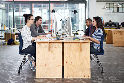 Buy stock photo Shot of a group of young office workers sitting at their work stations