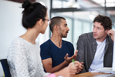 Buy stock photo Shot of a group of young coworkers talking at a deask