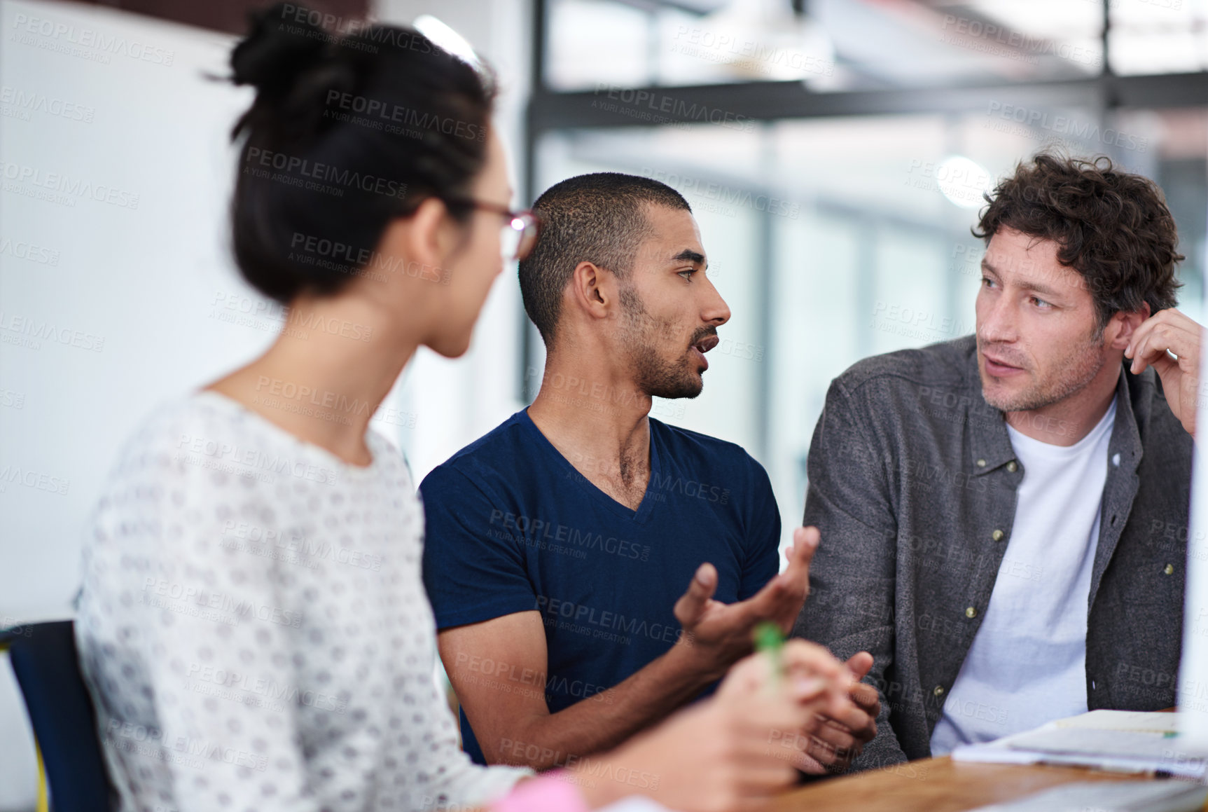 Buy stock photo Shot of a group of young coworkers talking at a deask