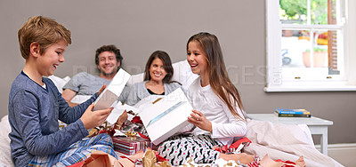 Buy stock photo Excited kids, parents and bed with gifts for Christmas, birthday or surprise together at home. Happy children or siblings opening presents, boxes or celebration in bedroom with mom and dad at house