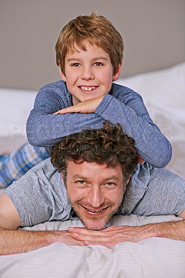 Buy stock photo Shot of a father and son lying on a bed