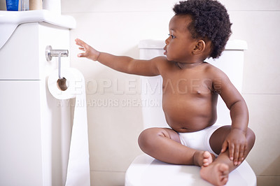 Buy stock photo Shot of a baby boy sitting on the toilet and reaching for the toilet paper