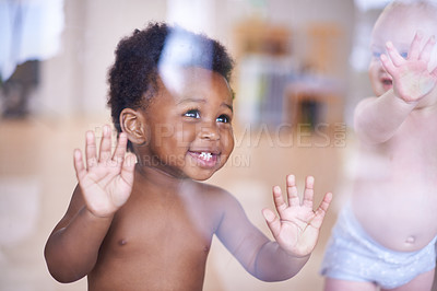 Buy stock photo Babies, happy and standing or window, natural and child development for toddler growth in preschool. Children, sensory education and touch with hand on glass, curious play with kids together