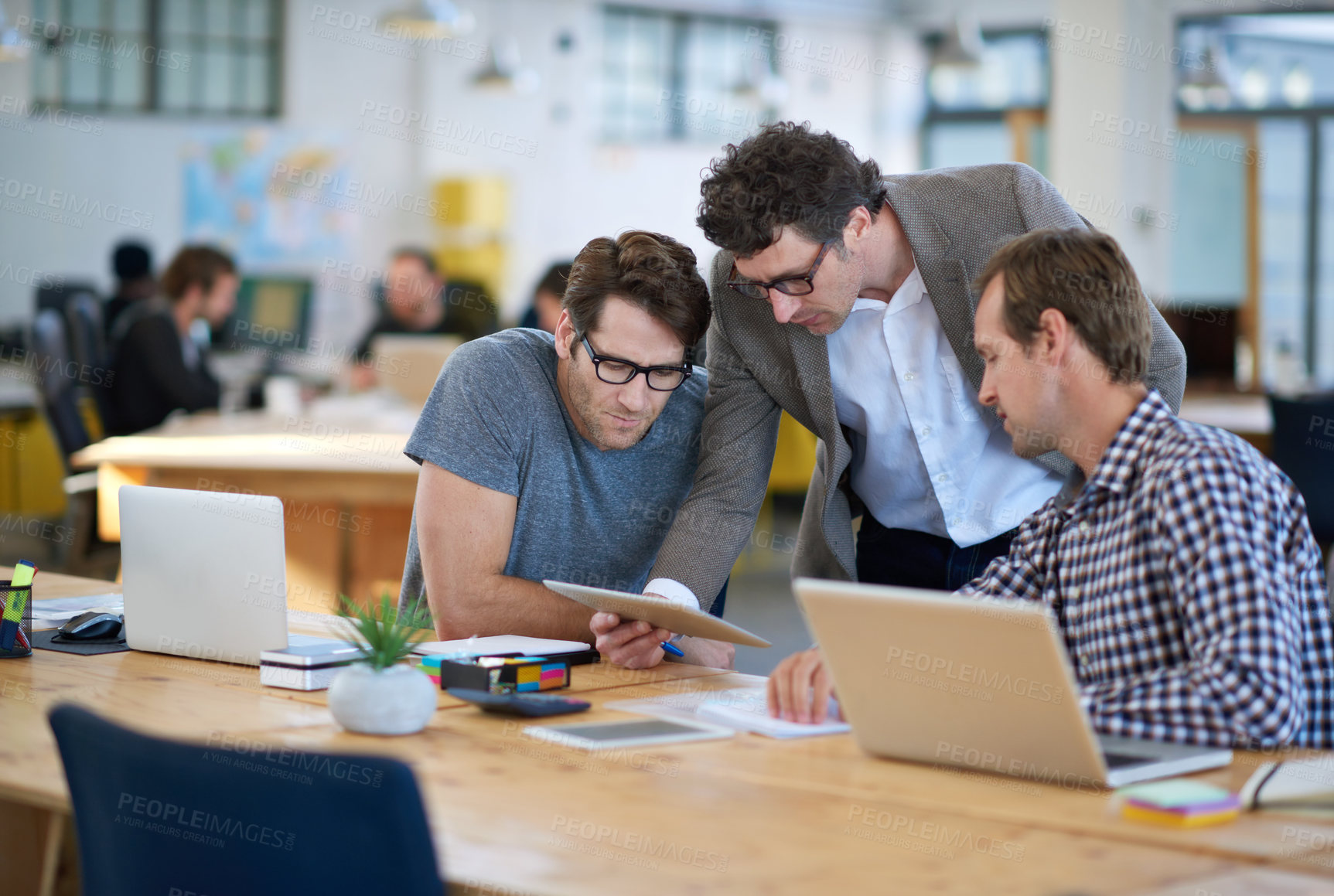 Buy stock photo Shot of business colleagues discussing matters with the help of wireless technology in their office