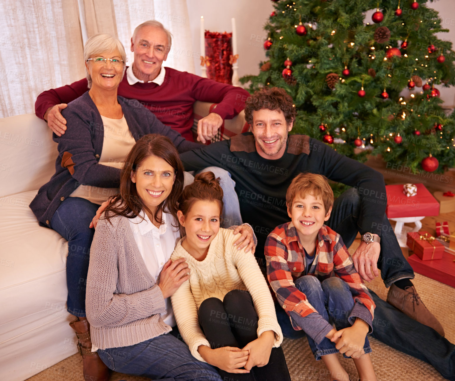 Buy stock photo Portrait of happy family at Christmas, generations on sofa in living room with Christmas tree, smile and happiness. Grandparents, couple and children on couch together at family holiday celebration.