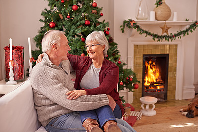 Buy stock photo Christmas, love and senior couple on sofa in home bonding and affection. Xmas, romance and elderly, retired woman sitting on lap of man and cuddle on couch by fireplace enjoying holiday time together
