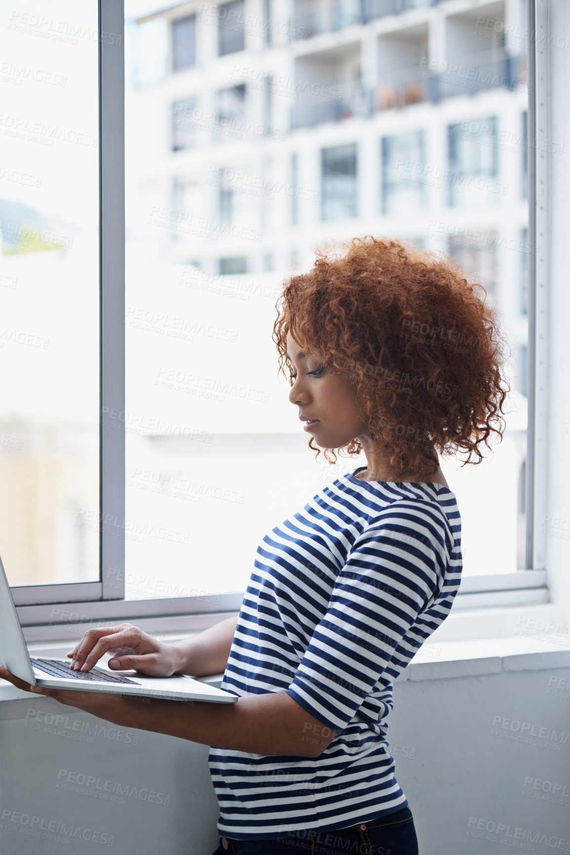 Buy stock photo Office, window and black woman typing on laptop with research or online communication on email. Creative, employee and working with computer to scroll information or news on internet for business