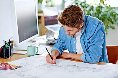 Buy stock photo Shot of a young architect working on some blueprints