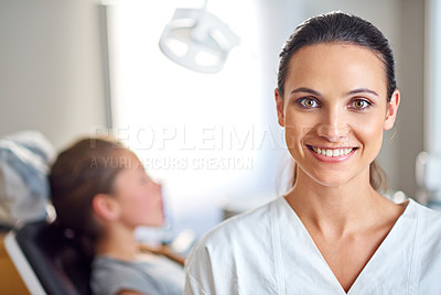 Buy stock photo A female dentist standing in her office with her child patient in the background