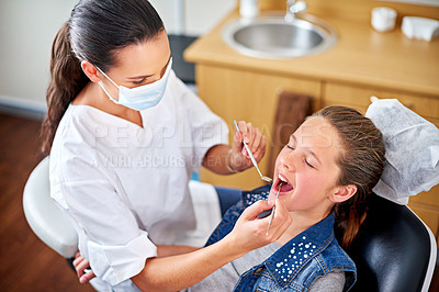 Buy stock photo Shot of a female dentist examining a little girl's teeth