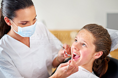 Buy stock photo Shot of a female dentist examining a young girl's teeth