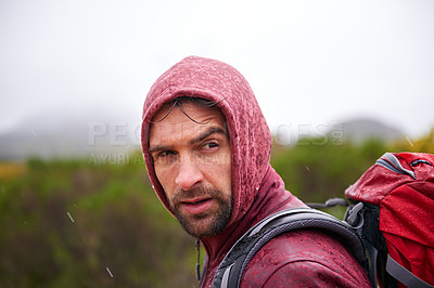 Buy stock photo Man, mountain and hiking in rain for fitness, wellness and exercise for training and adventure in environment. Young person with backpack and rock for workout and trekking in morning with weather