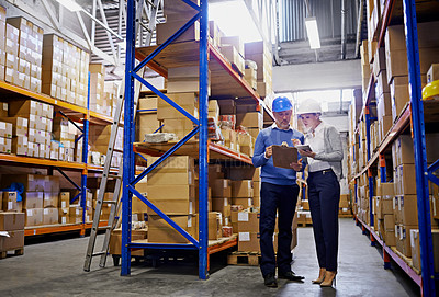 Buy stock photo Shot of a man and woman inspecting inventory in a large distribution warehouse