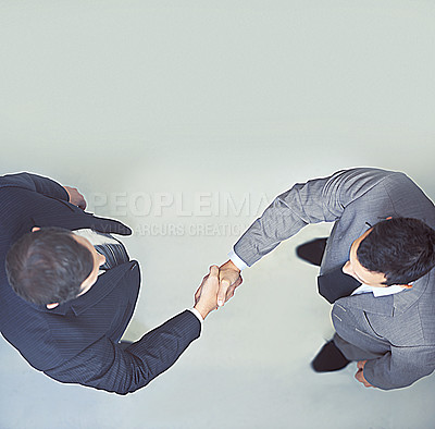 Buy stock photo Businessman, handshake and partnership above for agreement, deal or meeting on a gray studio background. Top view of man, colleagues or employees shaking hands for b2b or teamwork on mockup space