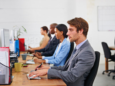 Buy stock photo Cropped shot of a group of coworkers sitting at their desks