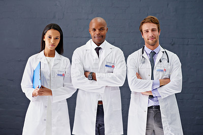 Buy stock photo Portrait of three doctors standing against a gray background