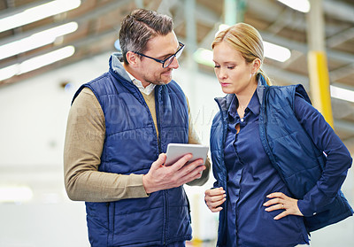 Buy stock photo Shot of two people using a digital tablet while working in a warehouse