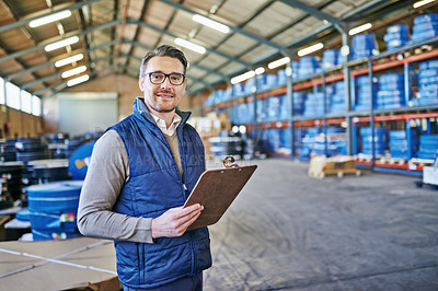 Buy stock photo Shot of a young man holding a clipboard in a warehouse
