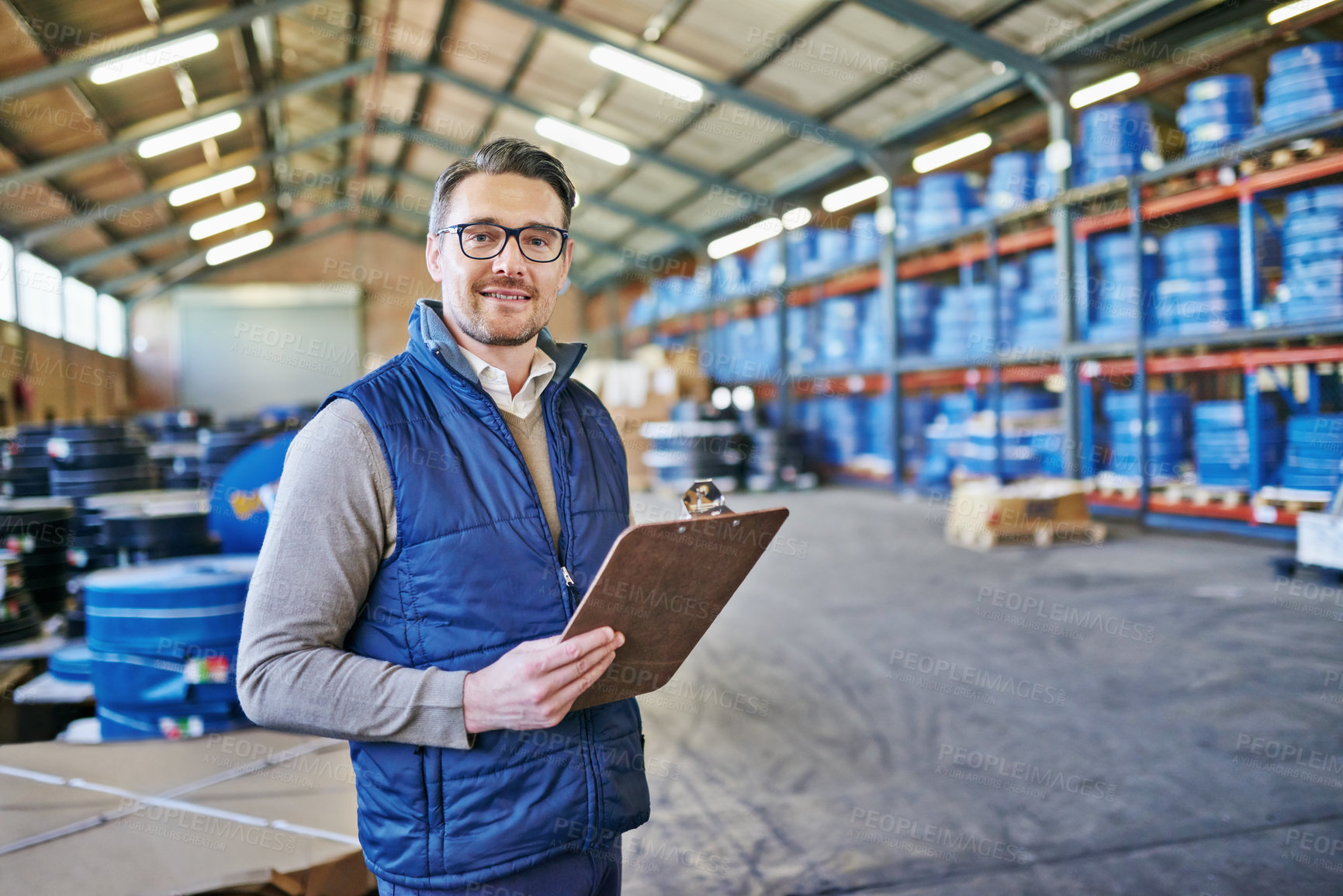 Buy stock photo Shot of a young man holding a clipboard in a warehouse