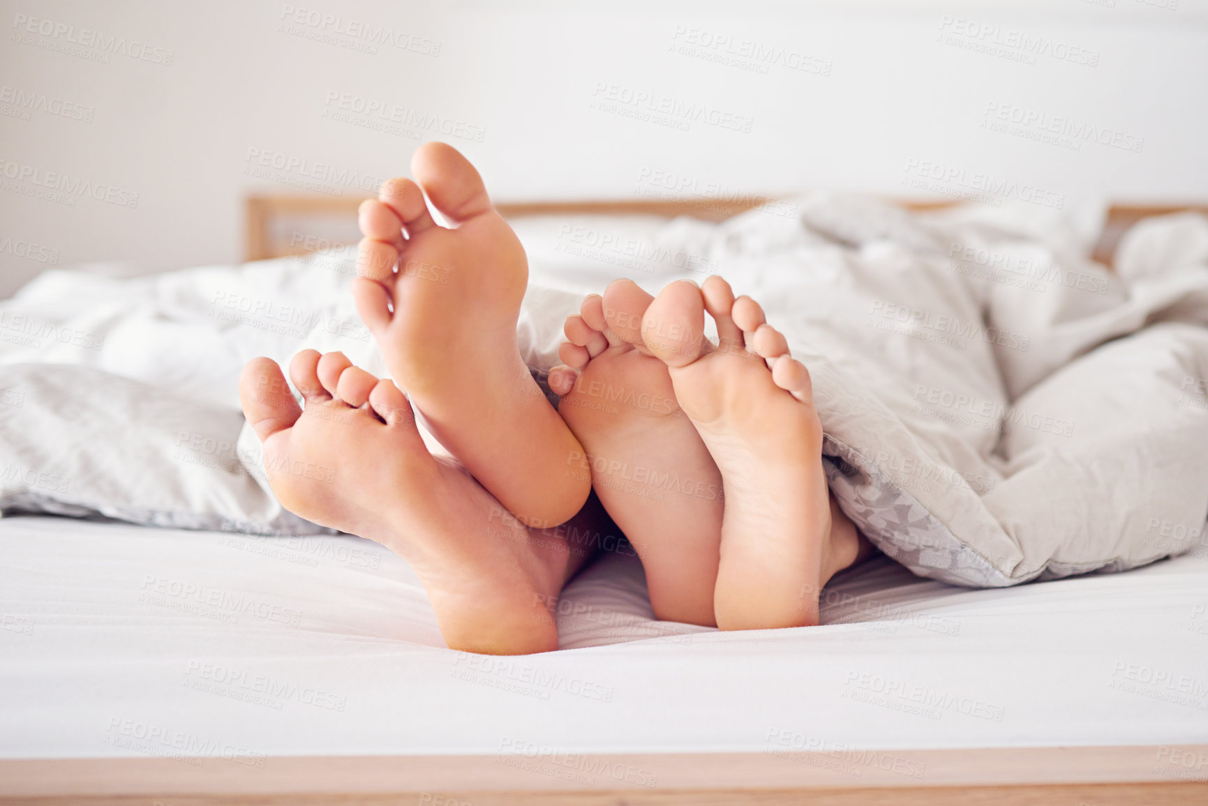 Buy stock photo Shot of a couple's feet poking out from under a duvet