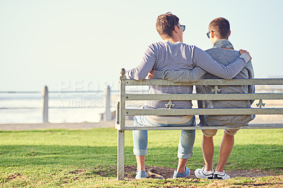 Buy stock photo Couple, park and bench for gay male people, ocean and promenade in nature. LGBT, love and hug or affection for married queer relationship, partner and honeymoon on holiday for bonding or relax