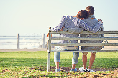 Buy stock photo Rearview shot of a young gay couple sitting together on a park bench