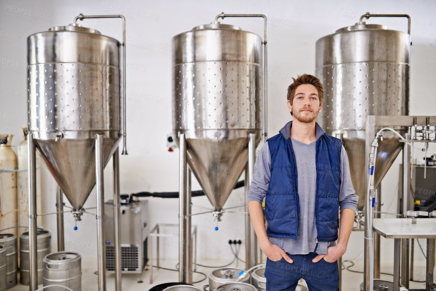 Buy stock photo Beer, production and man in portrait and factory or distillery for winery, alcohol and drink manufacturing. Worker or winemaker working by tank, metal or steel pipe of fermentation vessel in brewery