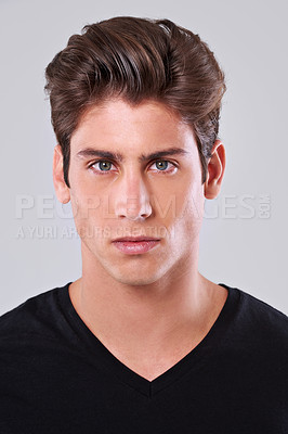 Buy stock photo Serious man, portrait and cool hairstyle with fashion or tshirt on a gray studio background. Closeup or face of masculine young model or male person with trendy hair, clothing or grooming treatment