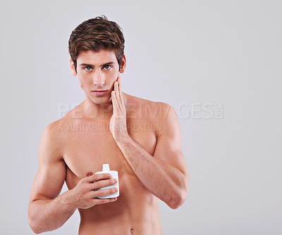 Buy stock photo Young man, portrait and lotion with cosmetics for skincare or cream on a gray studio background. Face of handsome male person or model with aftershave or container for hygiene on mockup space
