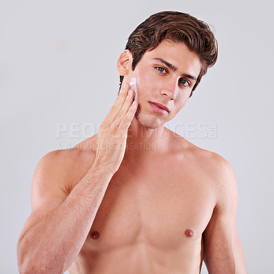Buy stock photo Handsome man, portrait and skincare with cream, grooming or hygiene on a gray studio background. Attractive male person or young model with lotion or moisturizer for facial treatment on mockup space