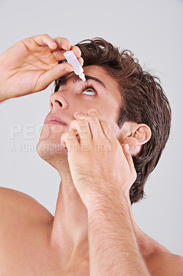 Buy stock photo Man, allergies and treatment with eye drops for sight, vision or care on a gray studio background. Male person or young model with pharmaceutical for optic hygiene, dry pupil or iris on mockup space