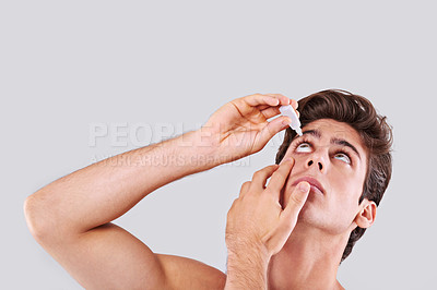 Buy stock photo Man, allergies and treatment with eye drops for infection, sight or vision on a gray studio background. Male person or young model with pharmaceutical for optic hygiene, dry pupil or iris on mockup