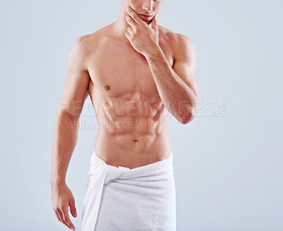 Buy stock photo Cropped studio shot of a handsome bare chested young man with his waist wrapped in a towel