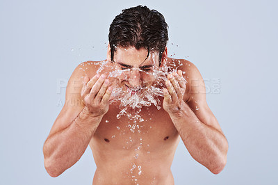 Buy stock photo Studio shot of a bare-chested young man splashing water on his face