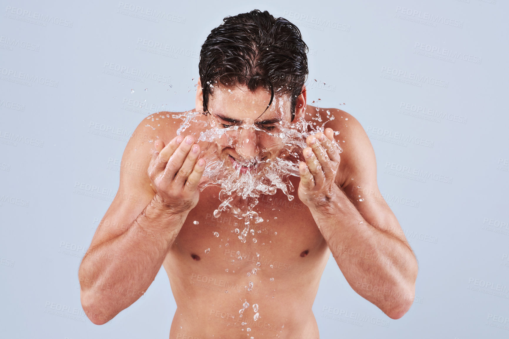 Buy stock photo Studio shot of a bare-chested young man splashing water on his face