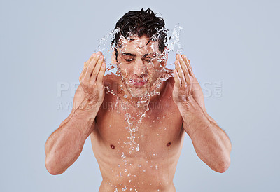 Buy stock photo Water splash, washing face and man on blue background for skincare, wellness and cleaning in studio. Dermatology, bathroom and person with liquid and shower for hygiene, grooming and hydration