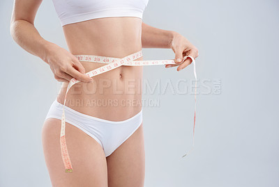 Buy stock photo Cropped shot of a young woman&#039;s waist with measuring tape